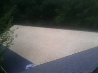 New OSB roof sheathing installed beside an existing shingle roof in Neola