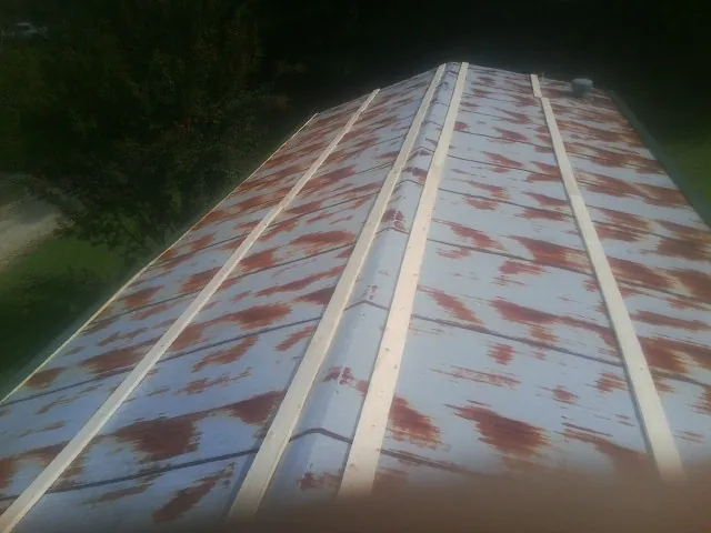 Rusted metal roof panels with new wood purlins before replacement — Storm Damage Roof Repair in Neola by Roofing Brothers