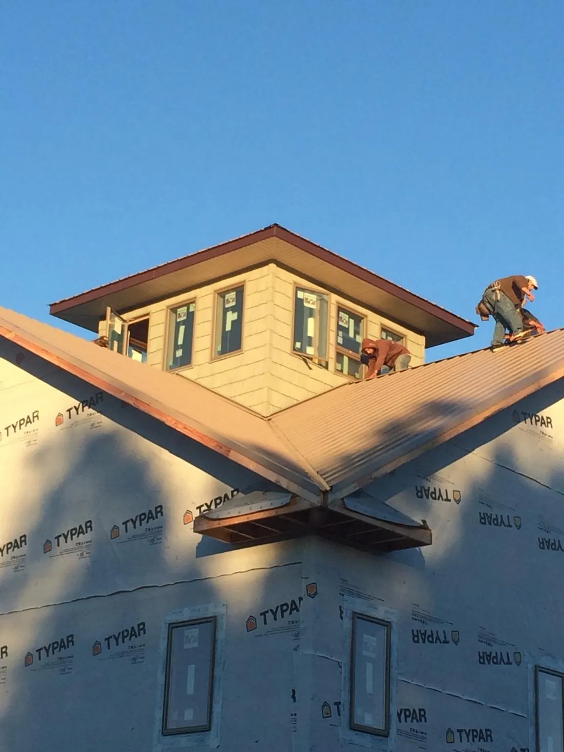 Roofers working around a rooftop cupola on a new metal roof at sunset — Roof Waterproofing in Neola by Roofing Brothers